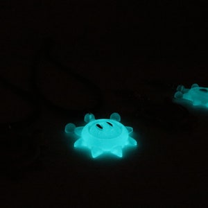May include: Two glow-in-the-dark, teal blue, star-shaped ornaments with a smiley face design.