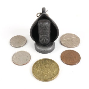 May include: A small, black, metal keychain shaped like a microphone with a silver base and a silver ring. The keychain is surrounded by five coins.