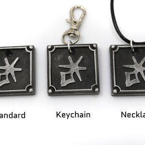 May include: Three silver-colored pendants with a black background and a silver symbol. The pendants are shown in three different styles: standard, keychain, and necklace.
