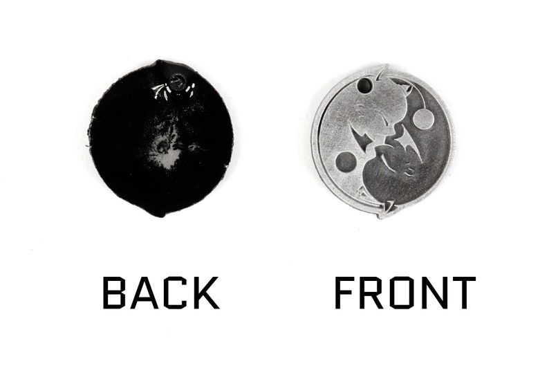 May include: A silver-colored metal charm with a yin yang design featuring two cats facing each other. The back of the charm is plain and black.