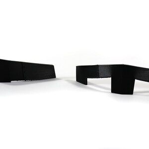 May include: Two black plastic corner guards, one with a straight edge and the other with a curved edge.