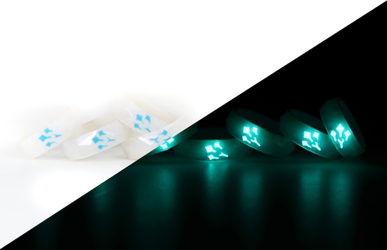 May include: A set of white silicone rings with a blue glow-in-the-dark design. The rings are shown in both daylight and dark conditions, highlighting their glow-in-the-dark feature.