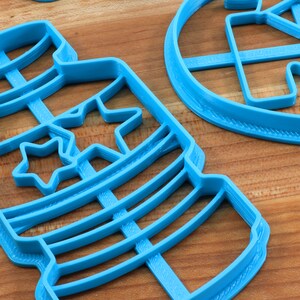Puede incluir: Cortadores de galletas de pl&aacute;stico azul en forma de frasco con estrellas y un c&iacute;rculo con una estrella en su interior.
