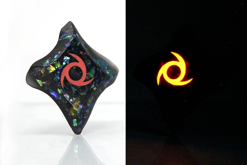 Pu&ograve; includere: Un ciondolo nero, iridescente, a forma di diamante con un motivo a stella rossa a tre punte. Il ciondolo brilla di arancione al buio.