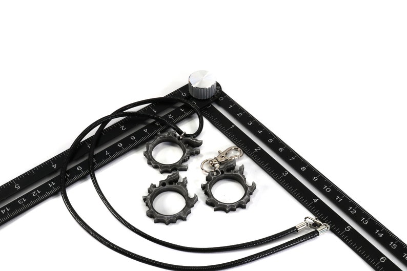 Puede incluir: Una cinta m&eacute;trica negra con un cord&oacute;n negro y tres anillos de metal plateado. La cinta tiene n&uacute;meros del 0 al 15.