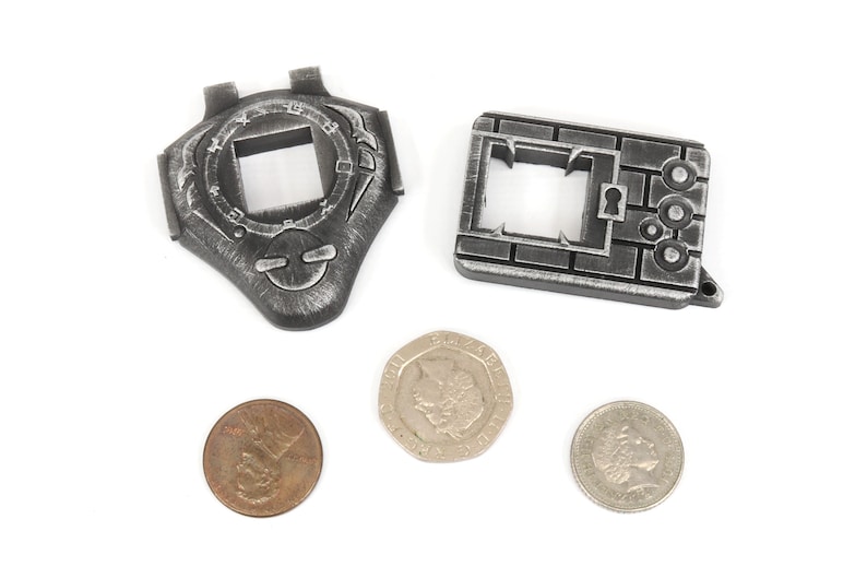 May include: Two silver-colored metal keychains with intricate designs. One keychain features a circular design with a square opening in the center. The other keychain features a rectangular design with a keyhole and a brick pattern. Three coins are also visible in the image.