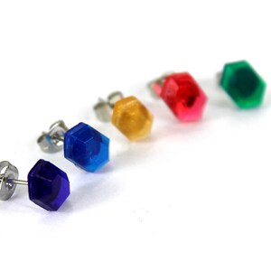 May include: Five pairs of stud earrings with different colored hexagonal gems. The colors are blue, purple, green, red, and yellow.