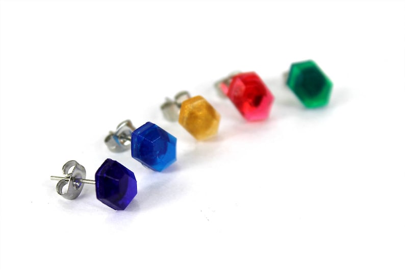May include: Five pairs of stud earrings with different colored hexagonal gems. The colors are blue, purple, green, red, and yellow.