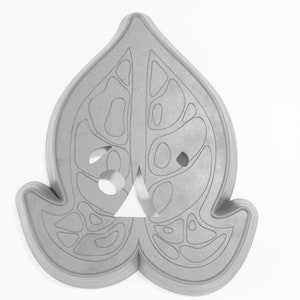 May include: A gray, leaf-shaped cookie cutter with a detailed design of holes and lines. The cutter is made of a durable material and is perfect for creating intricate cookies.