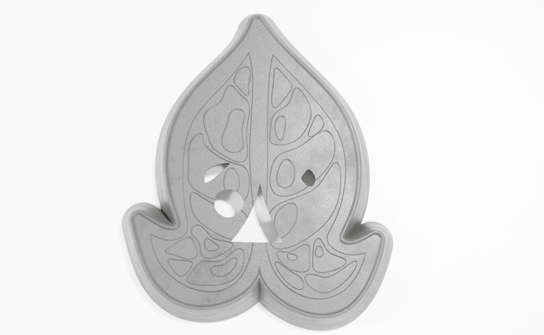 May include: A gray, leaf-shaped cookie cutter with a detailed design of holes and lines. The cutter is made of a durable material and is perfect for creating intricate cookies.