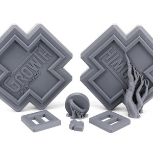May include: Two gray 3D printed plaques with the words "GROW WITH" and "HIM" on them. The plaques are shaped like a cross with a raised border. There are also three smaller gray 3D printed objects, including a basketball hoop, a small square, and a rectangle.
