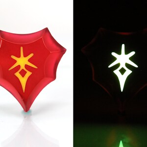 May include: A red, heart-shaped, glow-in-the-dark pendant with a yellow symbol inside. The symbol is a star with a diamond in the centre.