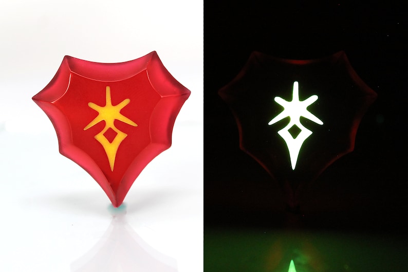 May include: A red, heart-shaped, glow-in-the-dark pendant with a yellow symbol inside. The symbol is a star with a diamond in the centre.