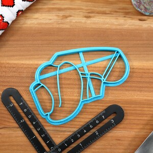 May include: A blue plastic cookie cutter shaped like a boxing glove.