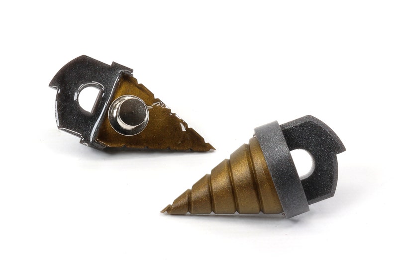 May include: Two metal drill bits with a gold and silver finish. One bit has a stepped, conical design, while the other has a flat, triangular shape. Both have a circular hole and a silver rivet.