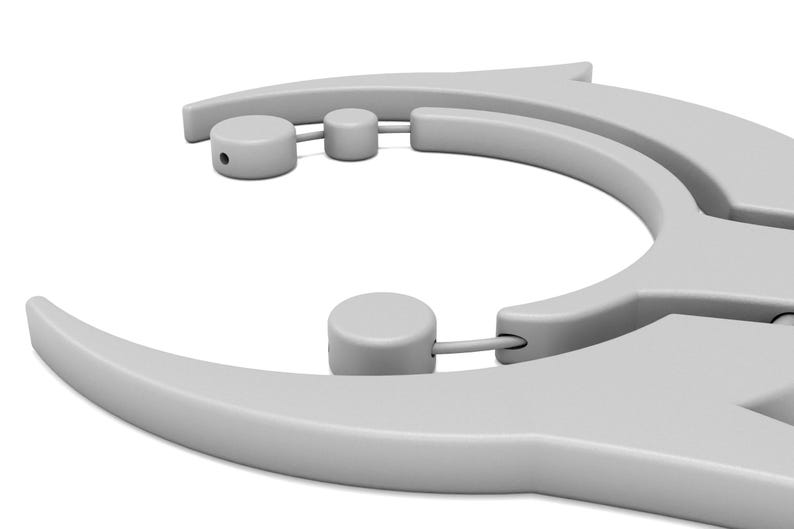 May include: A close-up of a light gray, plastic tool with a curved design. The tool has a series of rounded cylinders and a pointed end. The object is set against a white background.