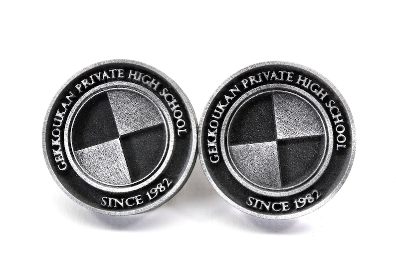 Pu&ograve; includere: Due spille in metallo color argento con un design a scacchi bianco e nero. Le spille recitano "Gekkoukan Private High School" e "Since 1982".