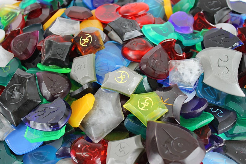 Puede incluir: Una colecci&oacute;n de piezas de juego de pl&aacute;stico transparente de varios colores, formas y tama&ntilde;os. Algunas piezas tienen un s&iacute;mbolo de rayo y el n&uacute;mero 25.