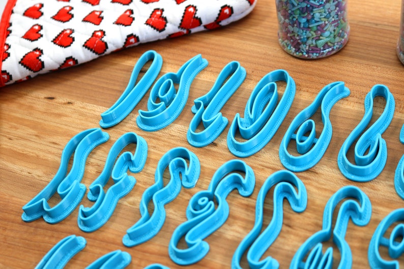 May include: A set of blue plastic cookie cutters shaped like the letters "Love" in a cursive font.