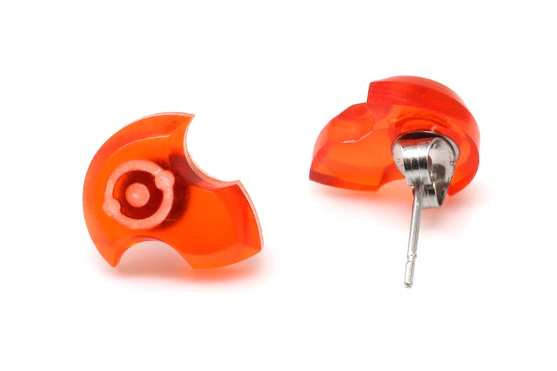 May include: A pair of orange resin earrings with silver posts. The earrings are shaped like a stylized heart.