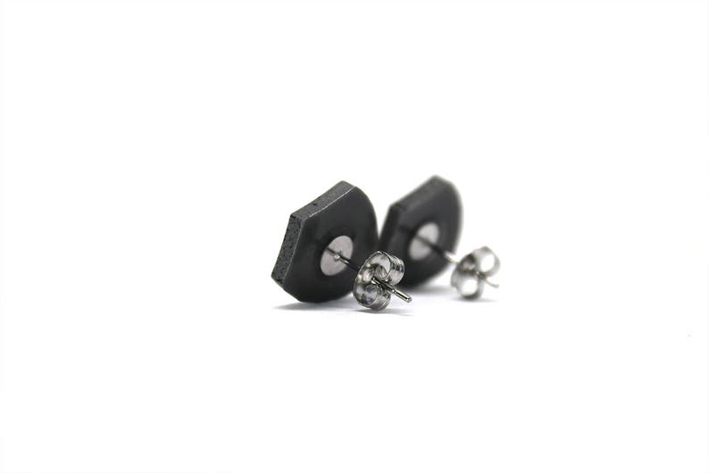 May include: A pair of black hexagonal stud earrings with silver posts.