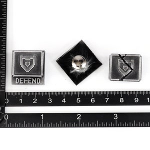 May include: Three silver-colored metal pins with a pixelated shield design. The first pin has the word "DEFEND" printed below the shield. The second pin is a blank back. The third pin has a crack through the shield.
