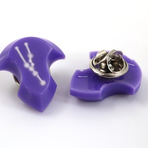 Op de afbeelding: Paarse emaille pin met een witte omtrek van het sterrenbeeld Stier. De pin heeft een metalen sluiting aan de achterkant.