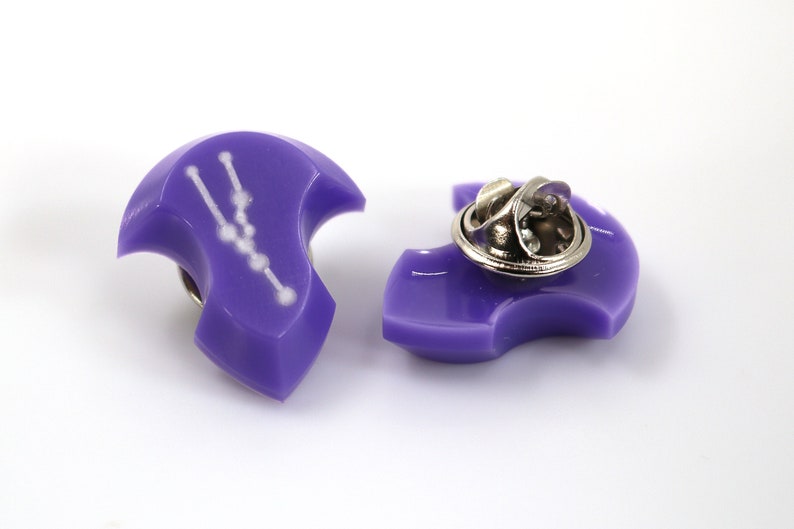 Op de afbeelding: Paarse emaille pin met een witte omtrek van het sterrenbeeld Stier. De pin heeft een metalen sluiting aan de achterkant.