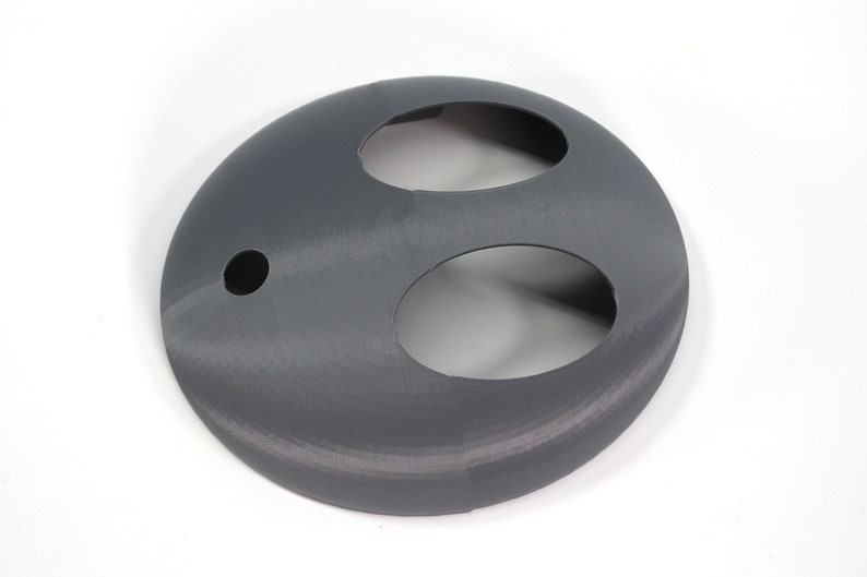 May include: A gray plastic 3D printed object with two oval-shaped cutouts and a small round hole.