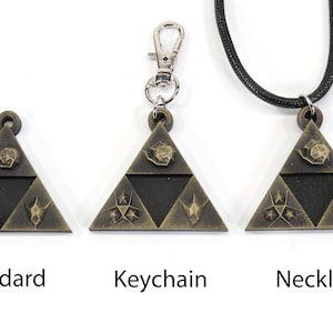 May include: Three versions of a gold-colored triangular pendant with a black center and various symbols. The pendant is available as a standard piece, a keychain, and a necklace.