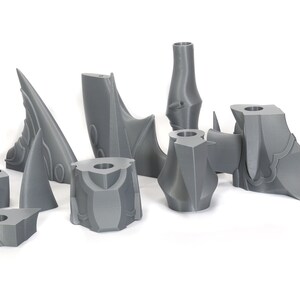 Peut inclure: Un ensemble de pi&egrave;ces en plastique gris imprim&eacute;es en 3D, probablement pour un kit de mod&eacute;lisme ou un jeu de figurines. Les pi&egrave;ces sont d&eacute;taill&eacute;es et complexes, avec des bords et des pointes ac&eacute;r&eacute;s.