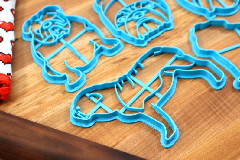 Może przedstawiać: Zestaw czterech niebieskich plastikowych foremek do ciasteczek w kształcie buldoga. Formy przedstawiają buldoga stojącego, siedzącego i leżącego.