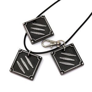 K&ouml;nnte beinhalten: Drei schwarze Metallanh&auml;nger mit einem silbernen Krallenmuster. Die Anh&auml;nger sind an einer schwarzen Schnurkette mit einem silbernen Verschluss befestigt.