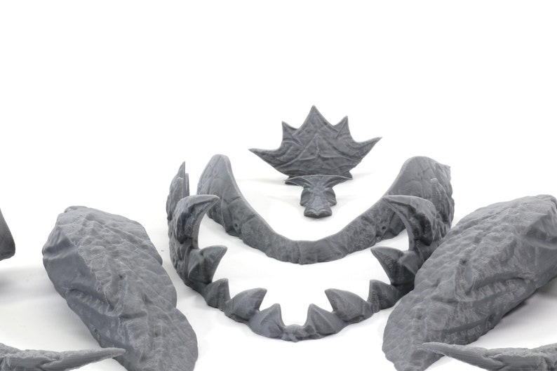 May include: A set of five gray plastic pieces that can be assembled to create a dragon head. The pieces include the top of the head, the jaw, and two side pieces.