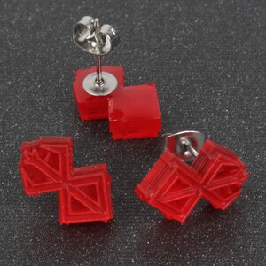 Puede incluir: Tres pares de pendientes de bot&oacute;n rojos geom&eacute;tricos con postes plateados. Los pendientes est&aacute;n hechos de pl&aacute;stico y tienen un dise&ntilde;o 3D.