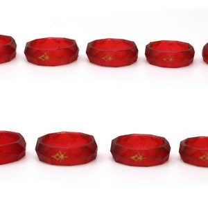 May include: Ten red silicone rings with a gold geometric design. The rings are all the same size and shape.