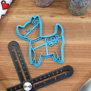 Puede incluir: Un cortador de galletas de pl&aacute;stico azul con forma de perro. El cortador tiene un dise&ntilde;o detallado con un collar y un patr&oacute;n en el cuerpo.