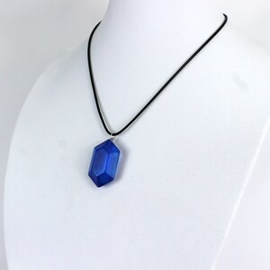 May include: A blue gemstone pendant necklace with a black cord.