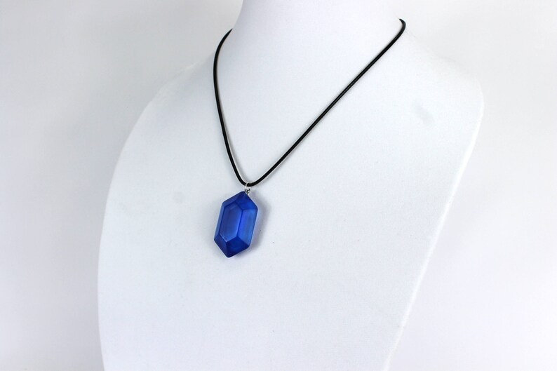 May include: A blue gemstone pendant necklace with a black cord.