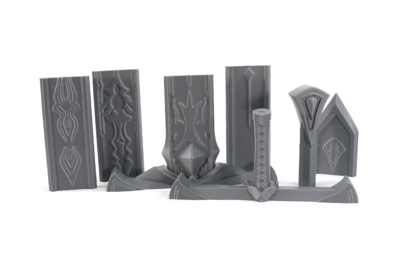May include: A set of gray plastic pieces for building a model sword. The pieces include the blade, hilt, and pommel. The pieces are detailed with intricate designs.