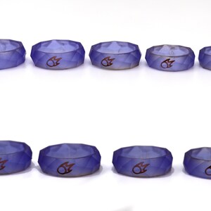 May include: Eight purple silicone rings with a raised flame design. The rings are in two rows of four, with the rings in the top row slightly larger than the rings in the bottom row.