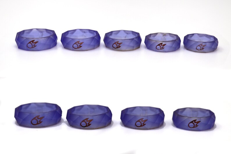May include: Eight purple silicone rings with a raised flame design. The rings are in two rows of four, with the rings in the top row slightly larger than the rings in the bottom row.
