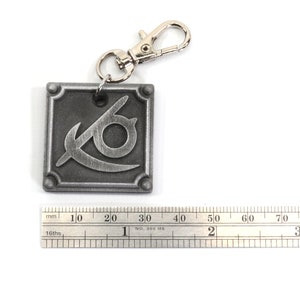 May include: A silver metal keychain with a square charm featuring a stylized eye symbol. The charm is about 3 cm wide.