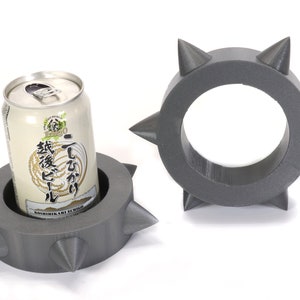 May include: Two grey, spiky, foam can holders. One holder has a can of Japanese beer inside.