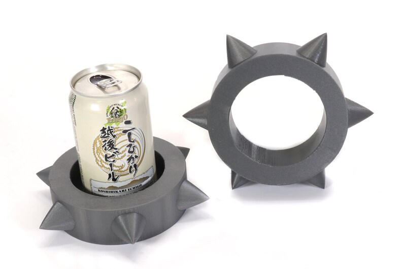 May include: Two grey, spiky, foam can holders. One holder has a can of Japanese beer inside.