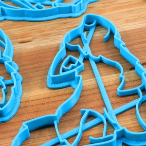 K&ouml;nnte beinhalten: Ein Satz mit drei blauen Plastik-Ausstechern in Tierform. Die Ausstecher liegen auf einer Holzoberfl&auml;che.