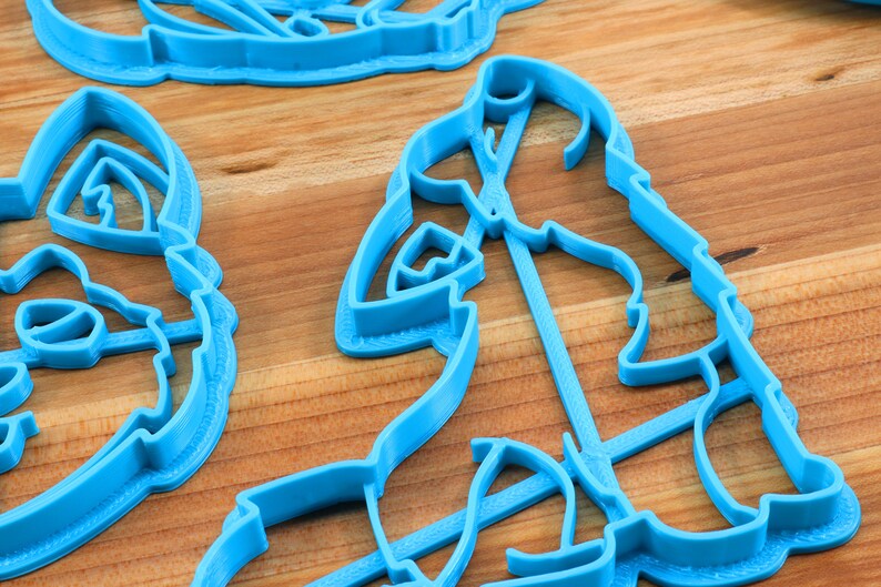 K&ouml;nnte beinhalten: Ein Satz mit drei blauen Plastik-Ausstechern in Tierform. Die Ausstecher liegen auf einer Holzoberfl&auml;che.
