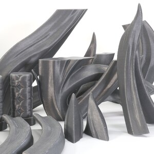 May include: A set of 3D printed, gray, abstract, geometric shapes. The shapes are made of a smooth, textured material and have a variety of curves and angles.