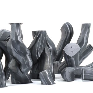 Puede incluir: Una colecci&oacute;n de 10 esculturas abstractas grises impresas en 3D con un acabado texturizado similar a la madera. Las esculturas est&aacute;n dispuestas en un grupo sobre un fondo blanco.