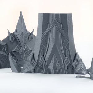 Puede incluir: Un conjunto de piezas de pl&aacute;stico gris impresas en 3D con dise&ntilde;os intrincados. Las piezas tienen forma de corona, torre y una peque&ntilde;a aguja.